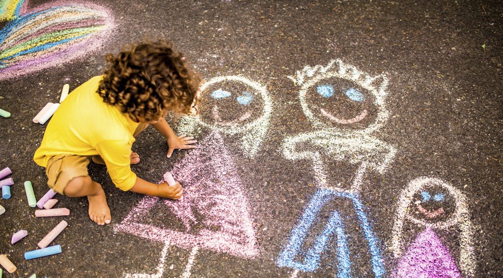 Ett barn ritar med kritor.