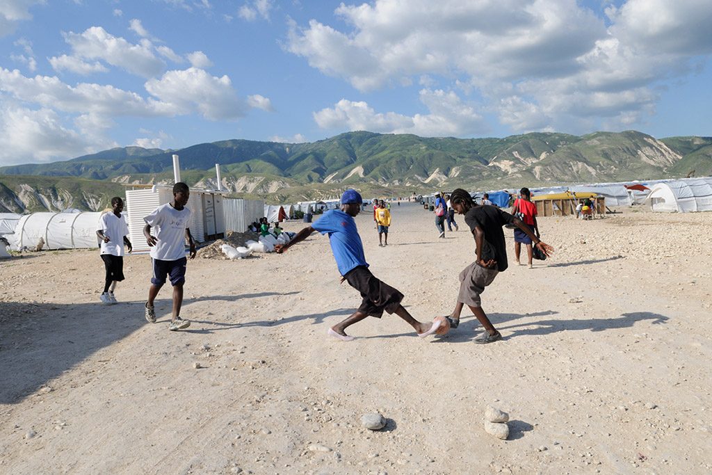 Pojkar spelar fotboll på en sandstrand.
