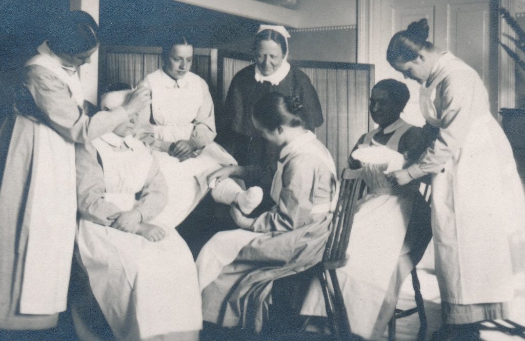 Ryhmä naisia harjoittelee sidontaa sairaanhoitajaopintojen osana. Helsingin Diakonissalaitoksen sairaala oli myös heidän harjoittelupaikkansa.