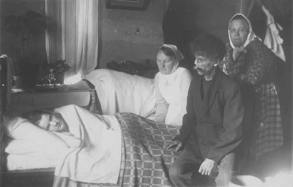 Naispotilas on vuoteessa. Hänen vierellään diakonissa sekä naisen vanhemmat. Vanha mustavalkoinen valokuva.