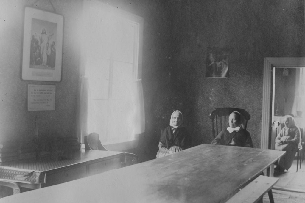 Kolme naista istuu hämärässä huoneessa.