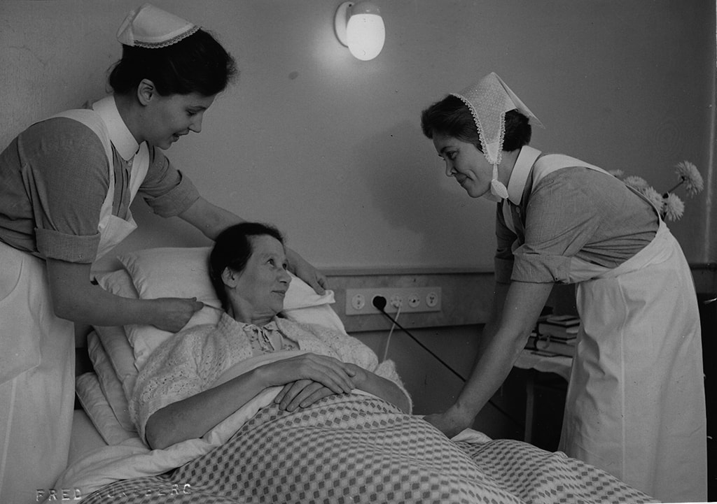 Kaksi sairaanhoitajaa kumartuneena potilaan lähelle.