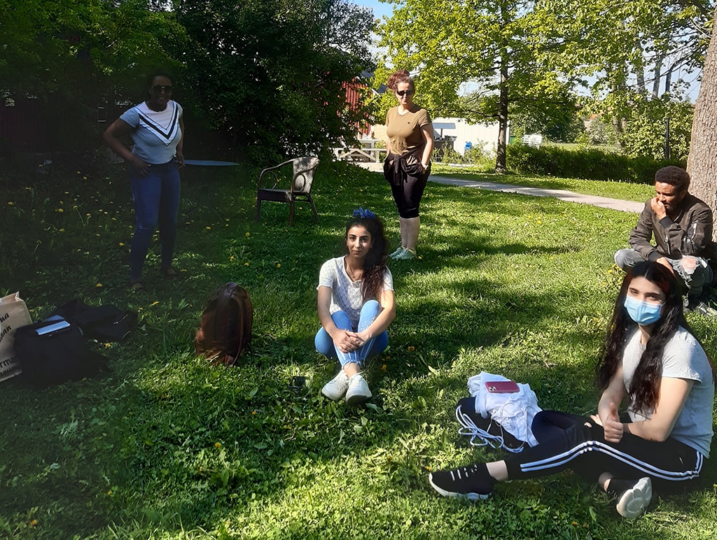 Ryhmä nuoria istumassa nurmikolla.