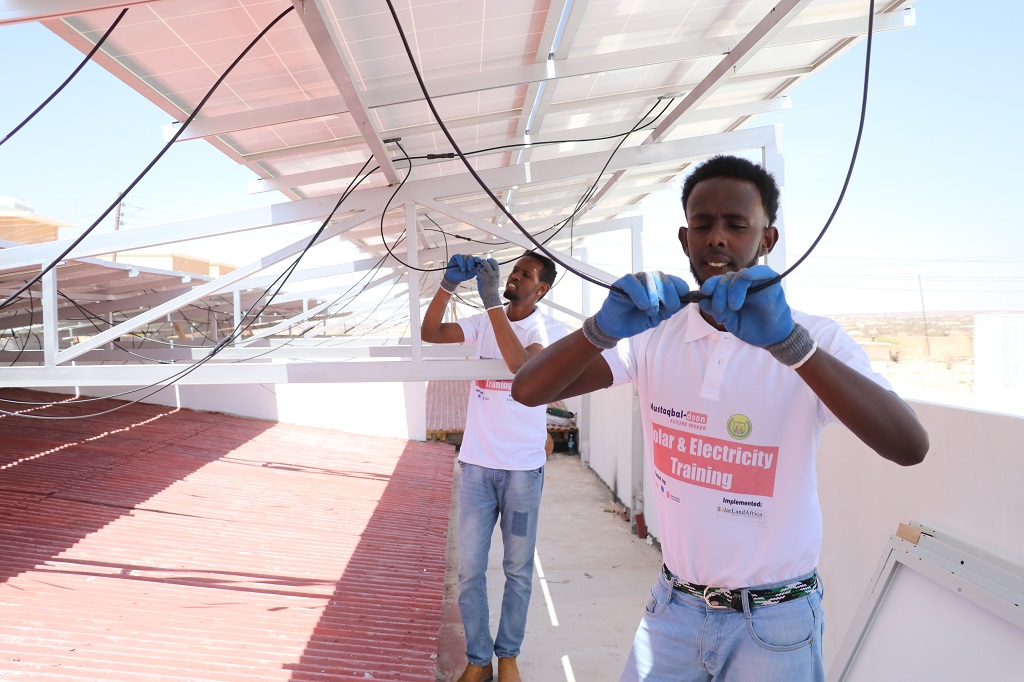 Kaksi nuorta harjoittelee aurinkopaneeleiden asentamista Somaliassa.