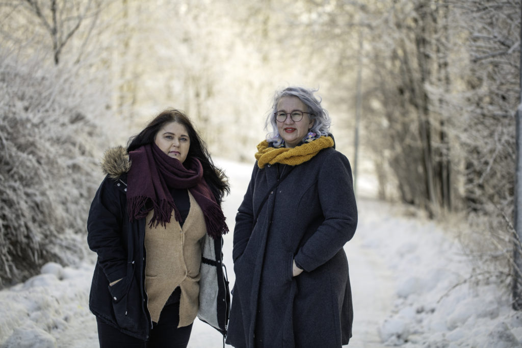 Kaksi naista seisoo talvisella tiellä.