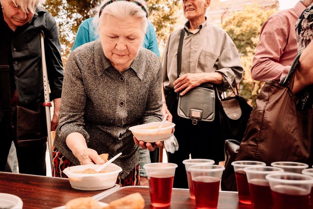 An elderly woman have a plate in her hand.