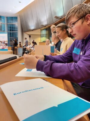 Nuoret istuvat Europarlamenttitalossa pyöreän pöydän ympärillä.
