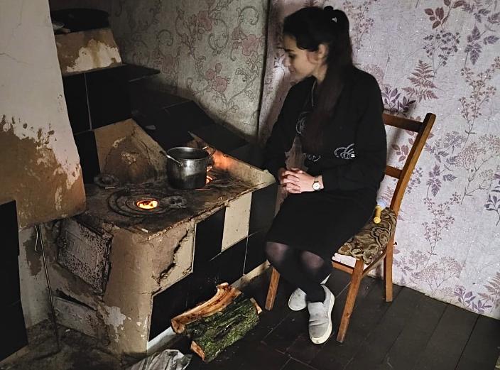 Romaninainen laittaa ruokaa huonokuntoisella puuhellalla Ukrainassa.