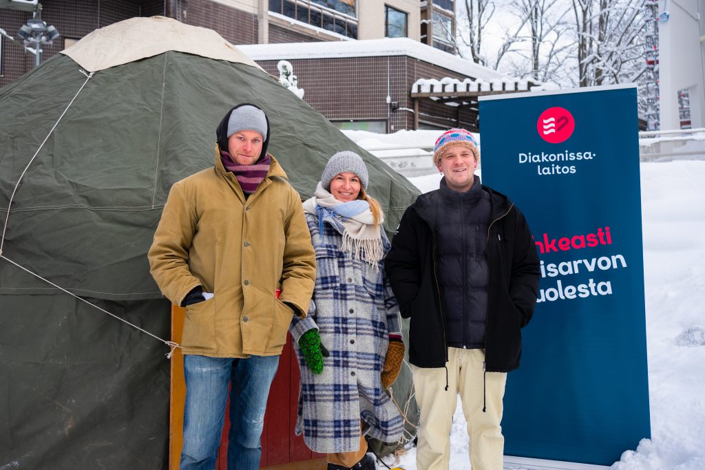 Kolme Kannelmäen D-aseman työntekijää seisoo vihreän jurtan edessä. 