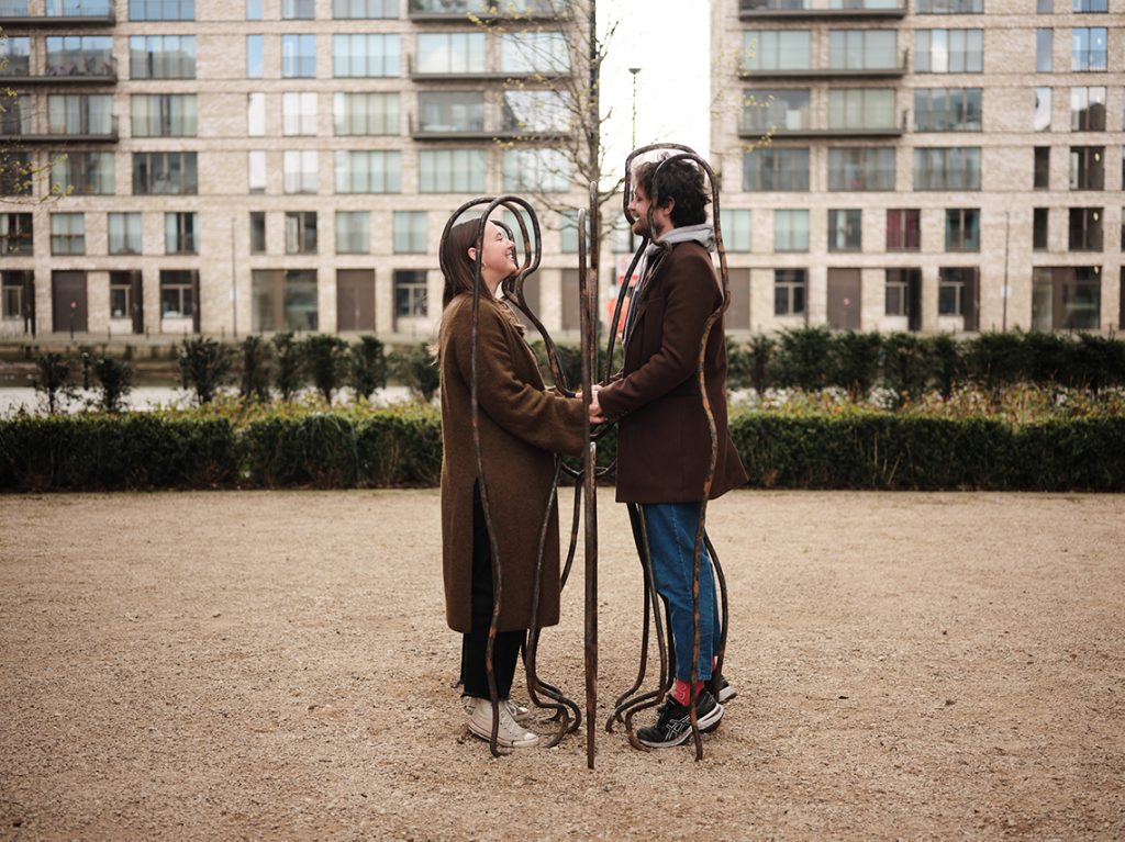 A man and a woman standing inside an art work.