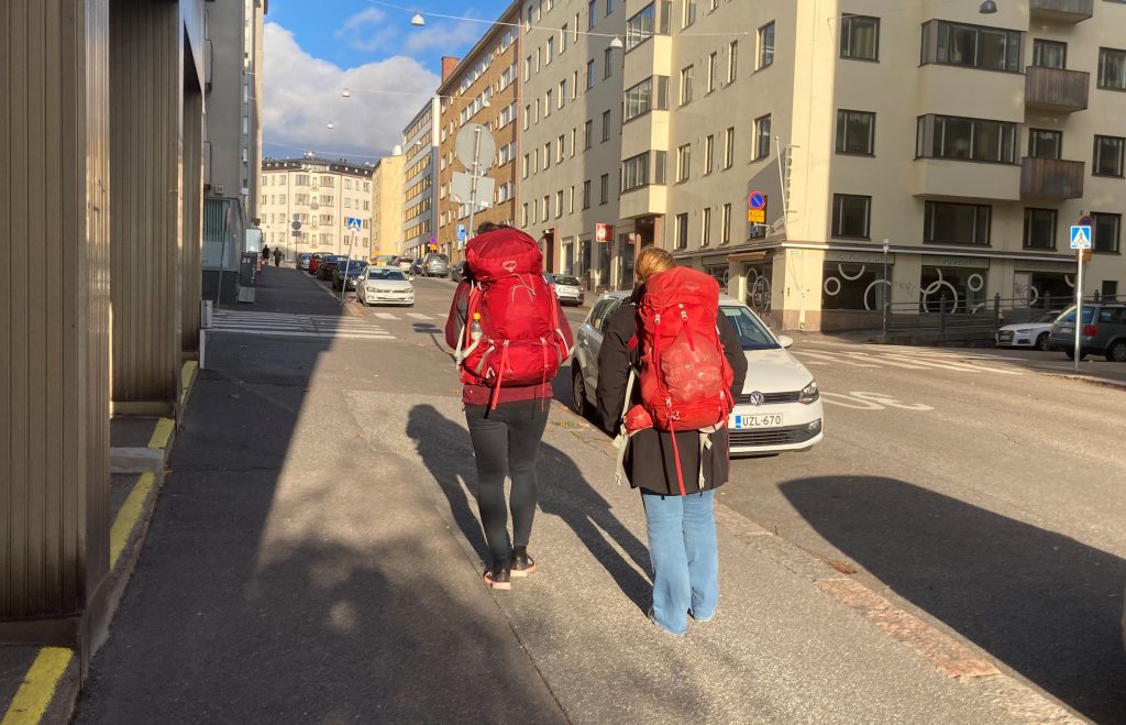 Kaksi reppuselkäistä ihmistä kävelee kadulla. 