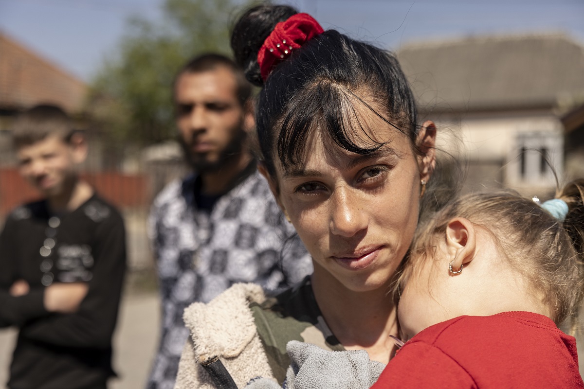 A woman carrying a child is looking directly at the camera.