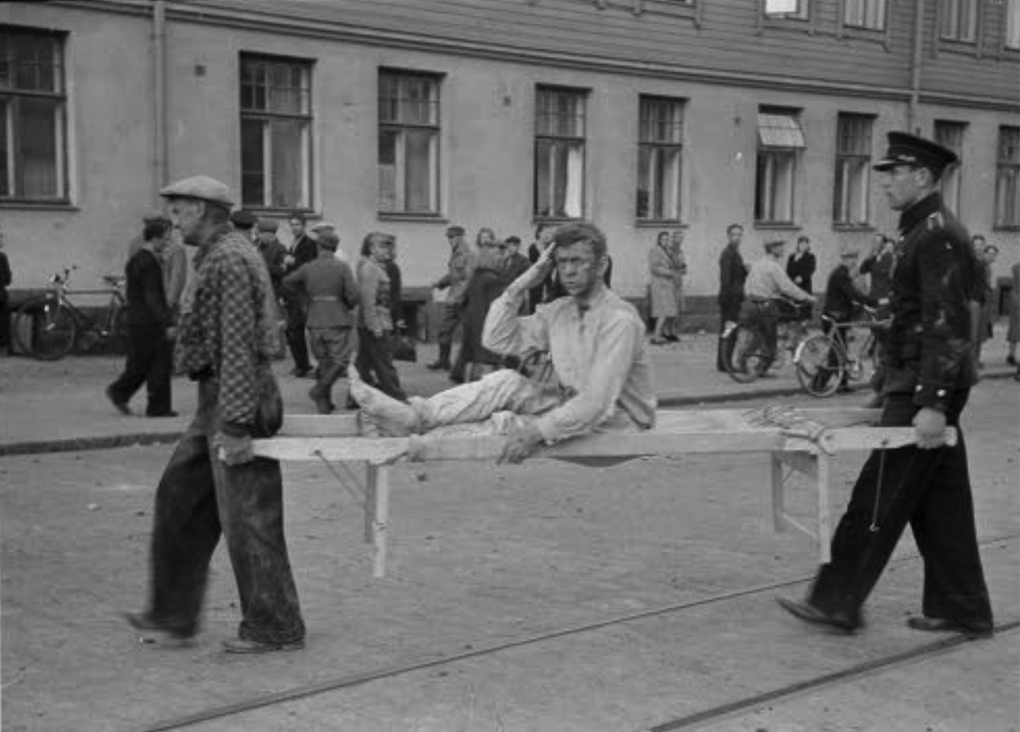 Miestä kannetaan paareilla hoitoon. Mies loukkaantui 9.7.1941. Oli sota-aika.