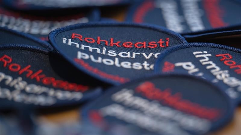 Tummansinisiä kangasmerkkejä, joissa lukee Rohkeasti ihmisarvon puolesta.