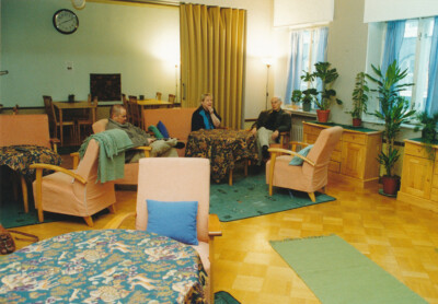 Kolme ihmistä olohuonemaisessa tilassa.