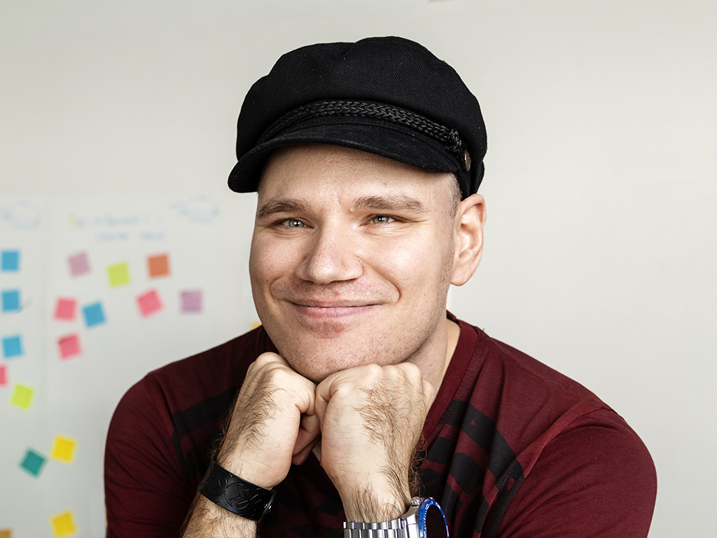 Mies nojaa kämmeniinsä ja hymyilee.