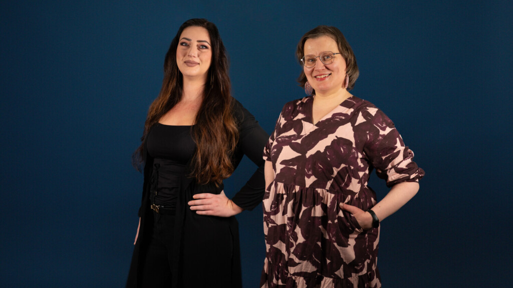 Kaksi naista katsoo hymyillen kameraan.