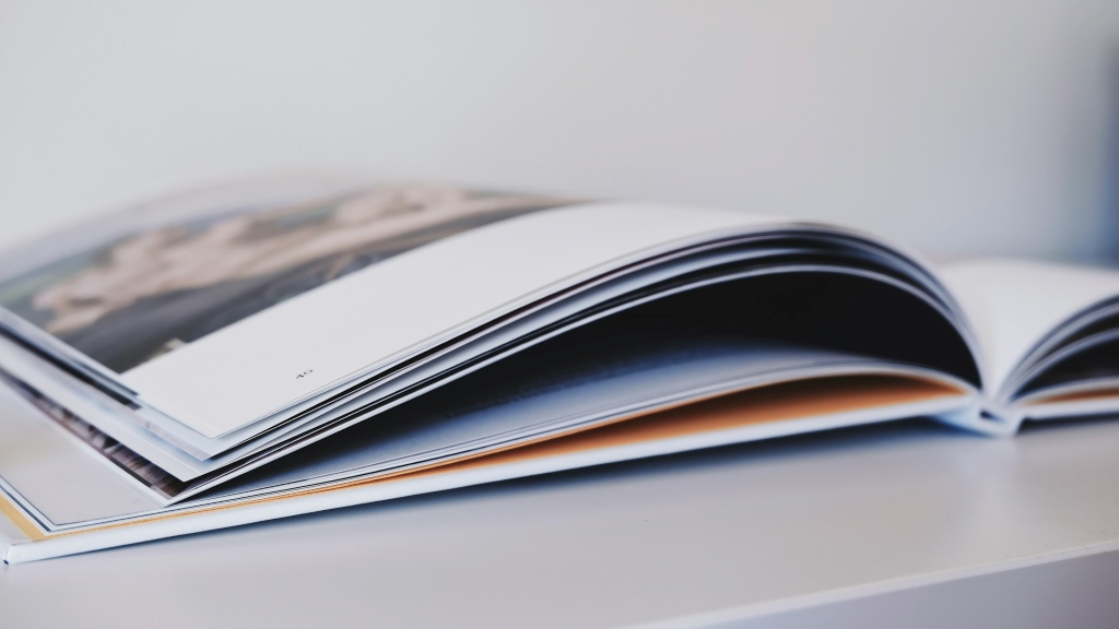 Pöydällä oleva avattu ohut kirja sivulta kuvattuna.