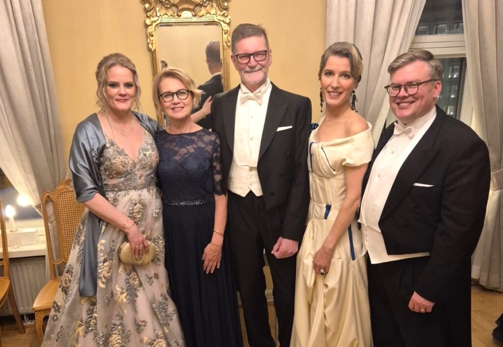 Viisi ihmistä juhla-asuissa Linnan juhlissa.